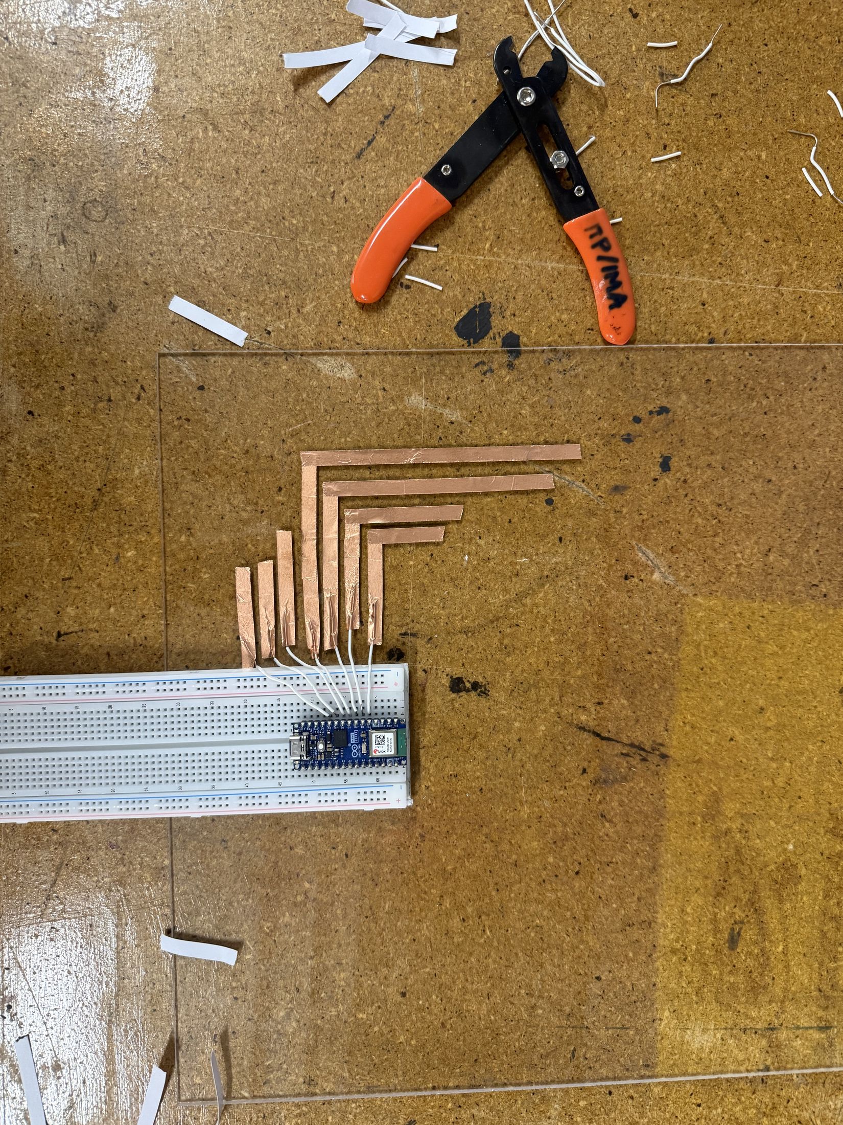 Copper strips fanned to a breadboard beside wire strippers.