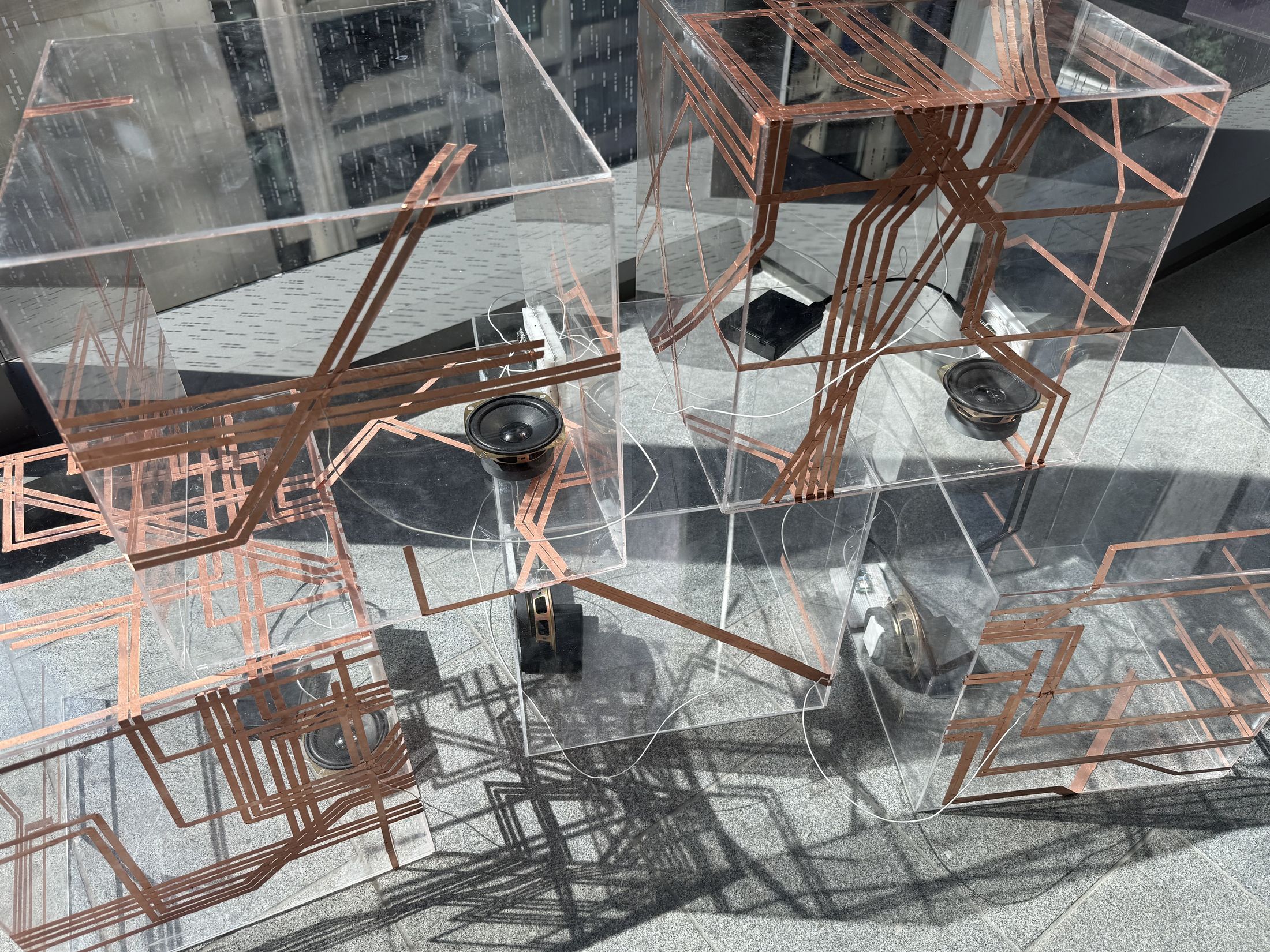 Close view of copper traces, speakers and boards inside clear cubes.