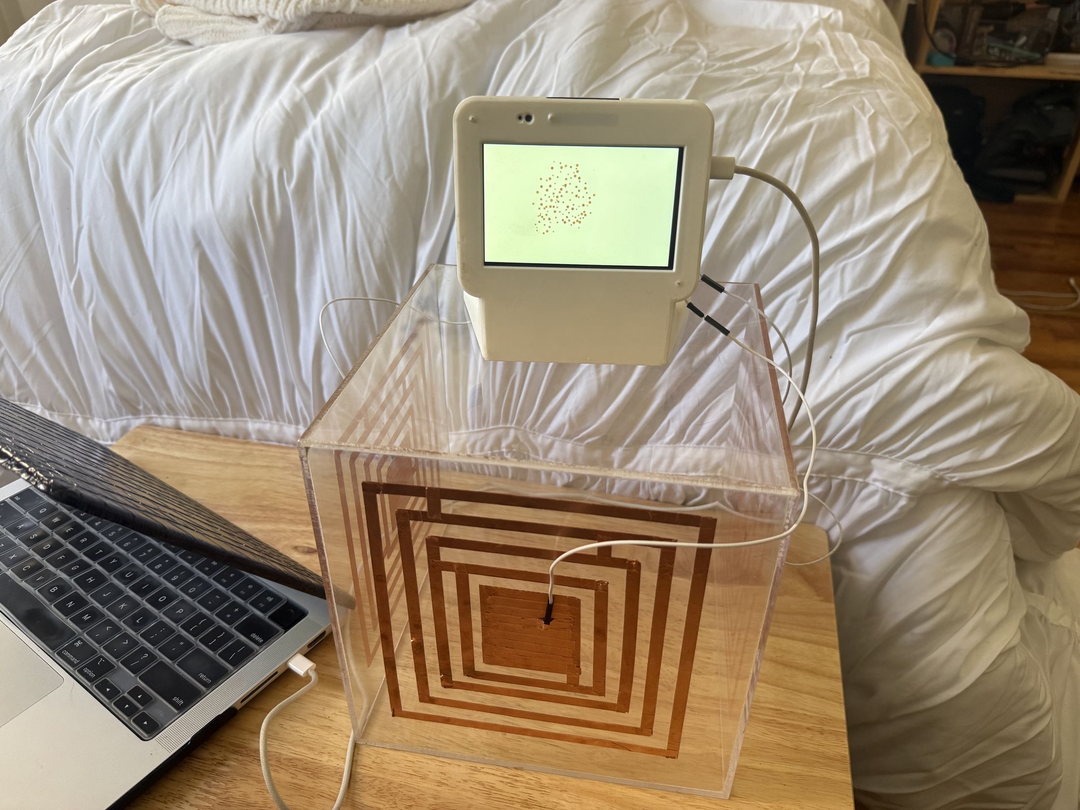 Acrylic cube with concentric copper squares and a small screen.