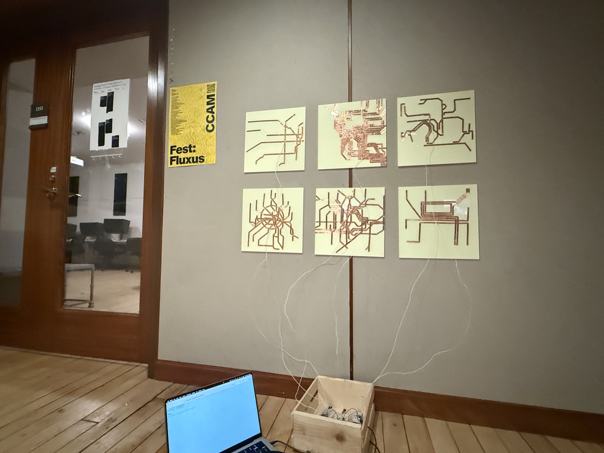 The maps wired down to a crate and a laptop on the floor, beside a glass door.